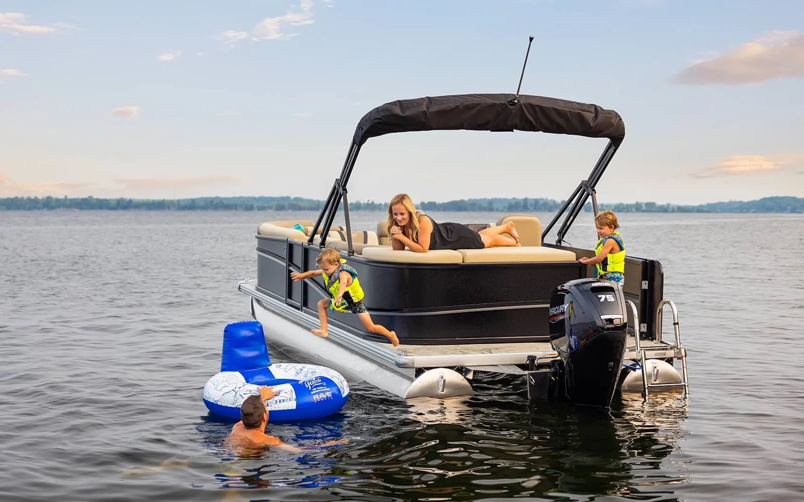 Kids climbing aboard an anchored pontoon with a water tube